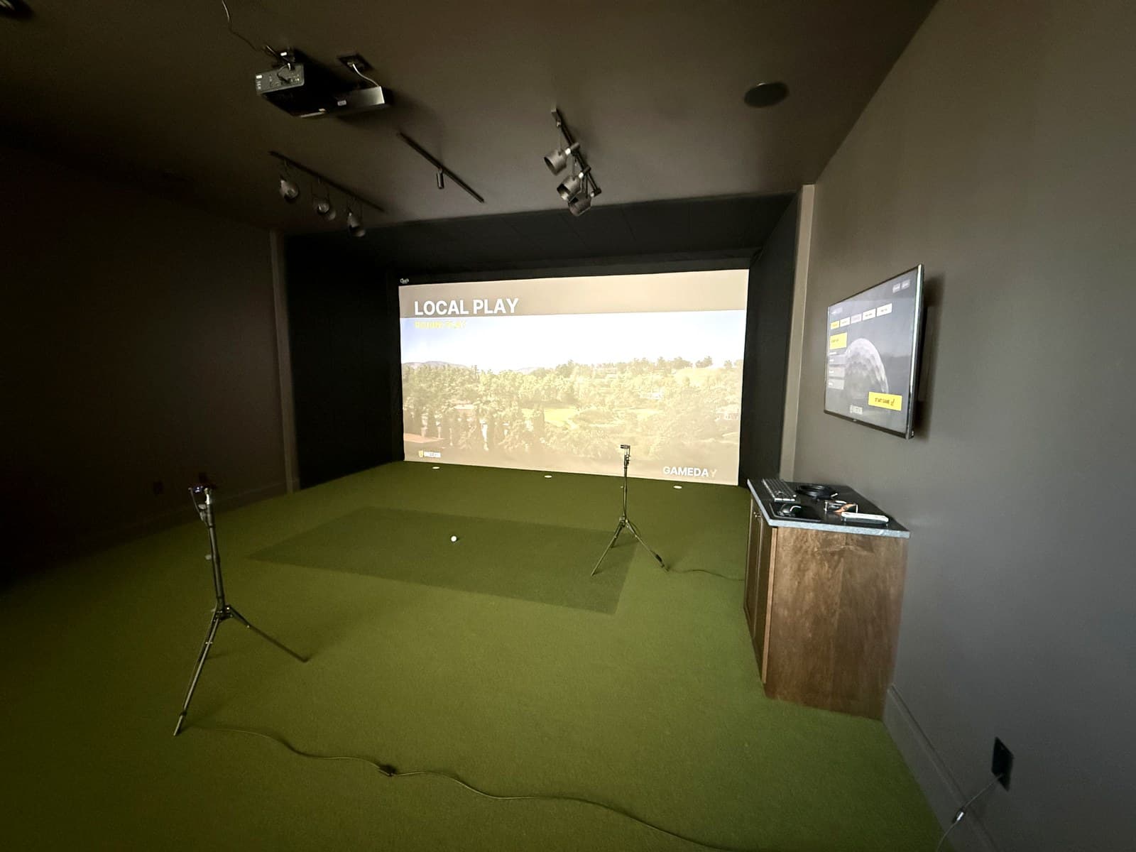 Finished basement golf simulator bay in Appleton with enclosure, impact screen, and hitting station.